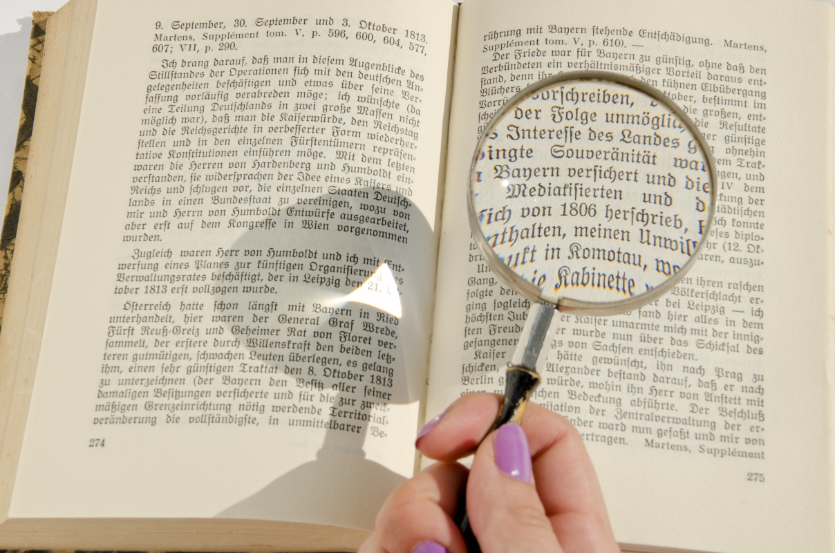 someone looking at a german text with a magnifying glass